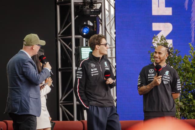 people microphones stage jackets caps blue black red green screen plants chairs event conversation audience