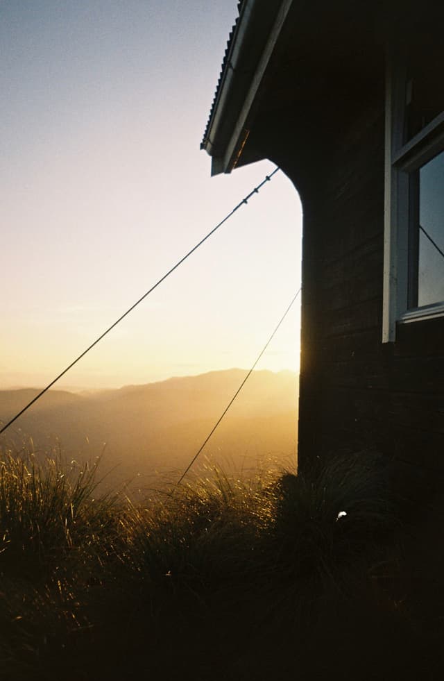 house window roof grass landscape mountain sunset sunrise silhouette sky horizon sunlight shadow cable yellow brown green blue