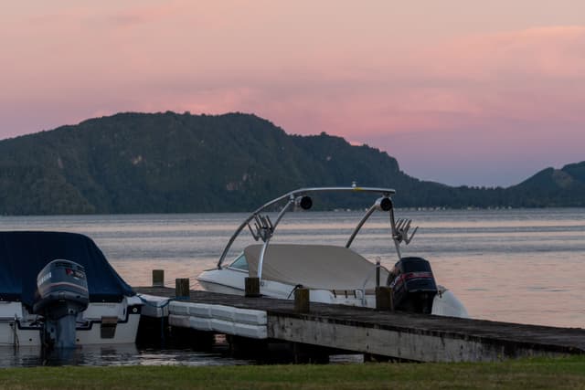 boat boats dock water lake mountain hills sunset sky pink blue grass pier motor reflection landscape nature outdoor serene calm