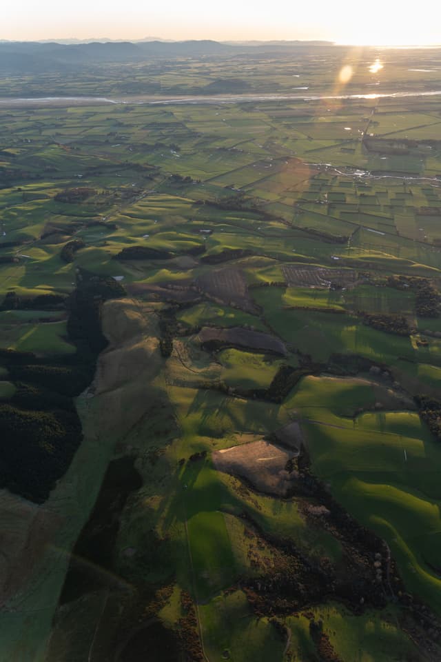 landscape hills fields farmland aerial view green sunlight horizon sky nature terrain countryside agriculture rural scenery panorama earth topography environment outdoors natural beauty geography sunlight shadows plains valleys plateau pasture meadows grassland vista sunlight primary color green
