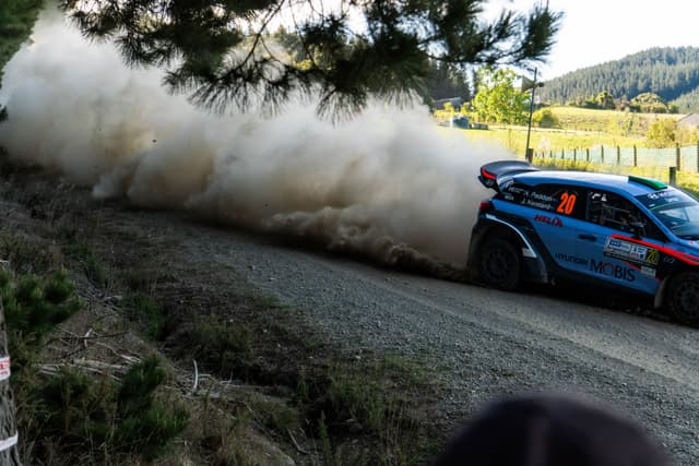 car rally race dirt road dust trees landscape motion speed blue green sky nature action outdoor vehicle competition sport forest countryside adventure excitement dynamic scenery environment track path trail racing energy power performance transportation drive journey travel exploration challenge thrill adrenaline motorsport