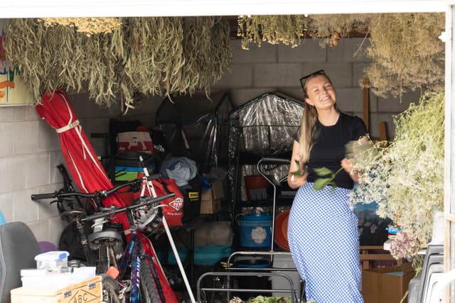 garage bicycle plants woman drying flowers storage boxes red blue green black gray white shelves tools equipment ceiling wall floor