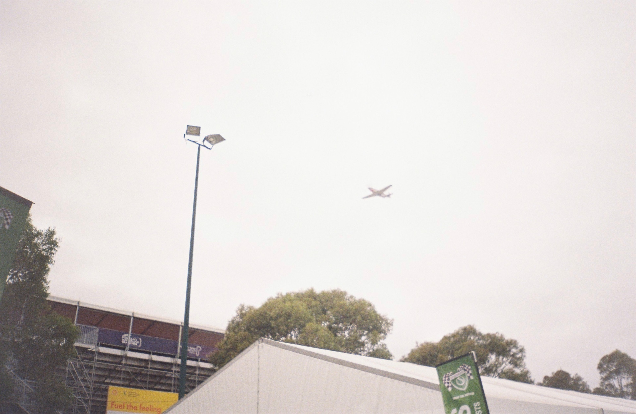 airplane sky lamp post trees building tent sign overcast gray