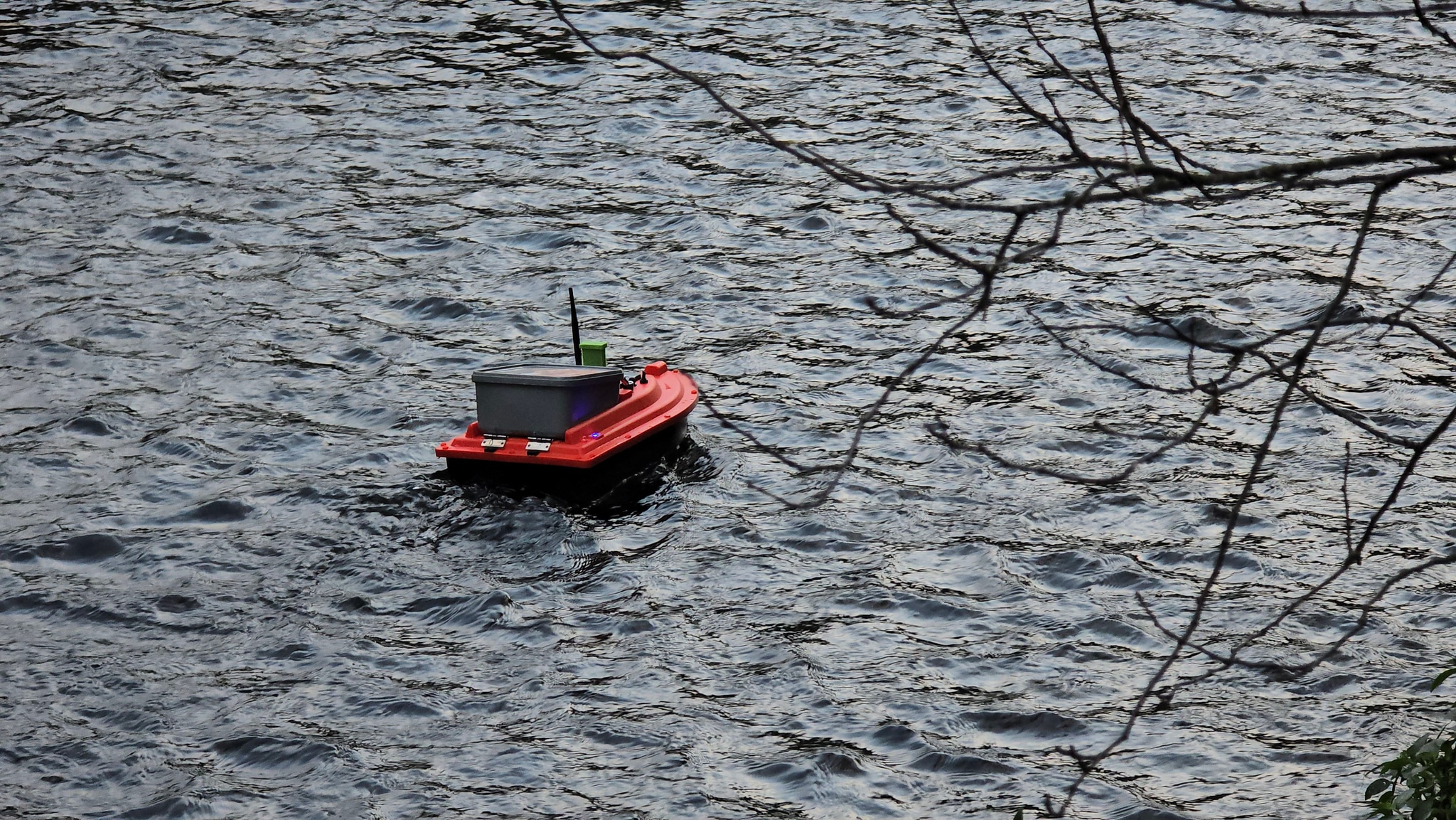 water boat red small vessel waves branches outdoor lake river floating gray