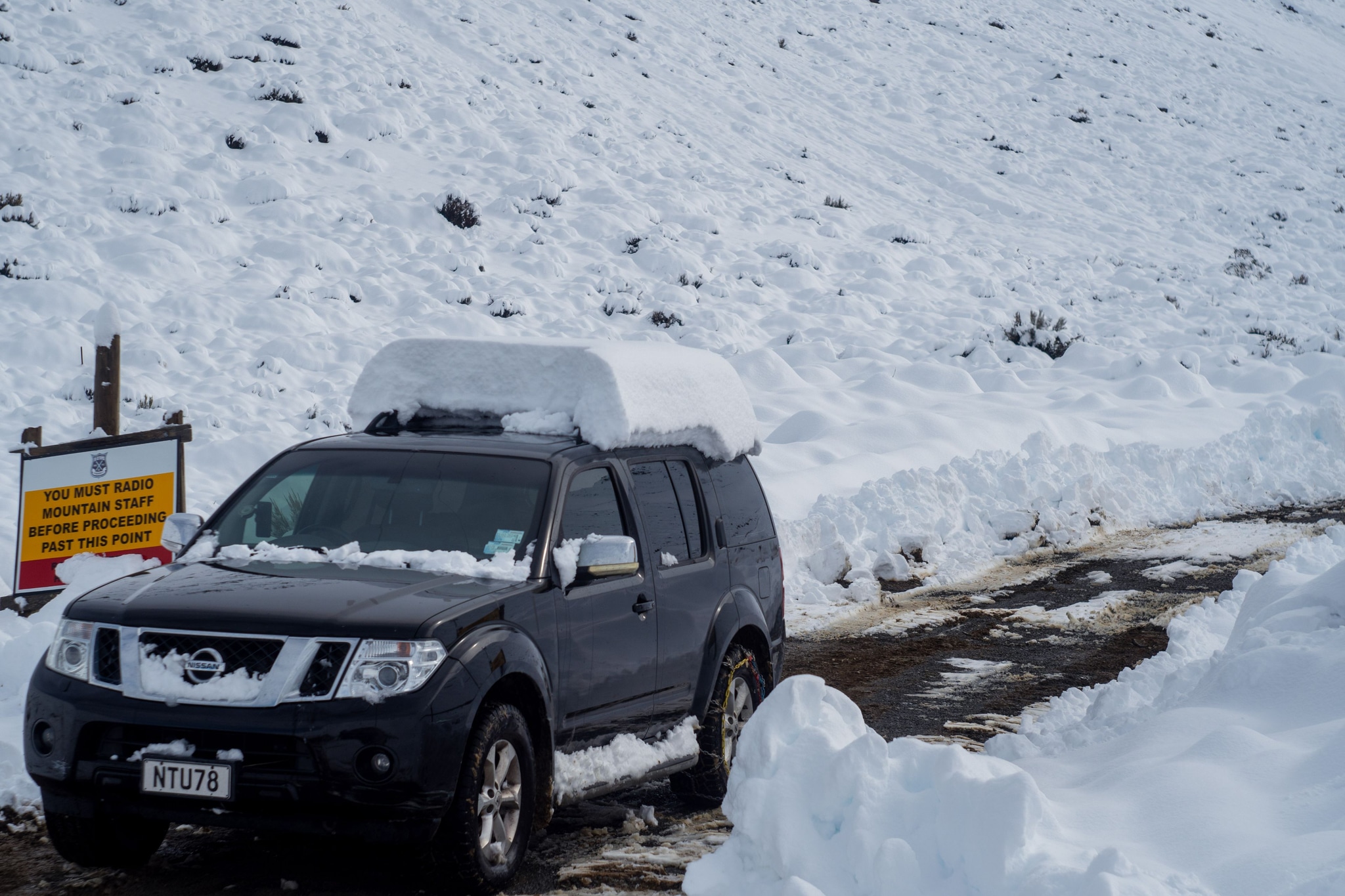 snow car vehicle road winter landscape mountain signboard snow-covered roof black white cold travel outdoor nature ice transportation path journey scenery frozen weather driving adventure trip exploration remote rugged terrain environment season automobile journeying expedition snowy primary-color-white
