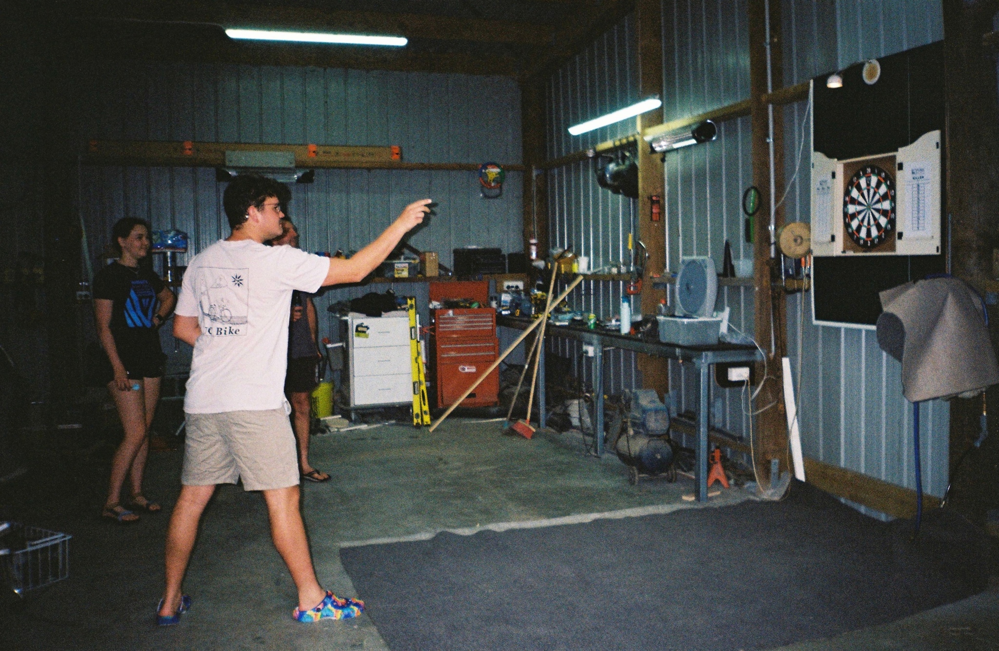 dartboard darts people throwing garage tools equipment shelves broom chair light blue red gray black white floor wall ceiling