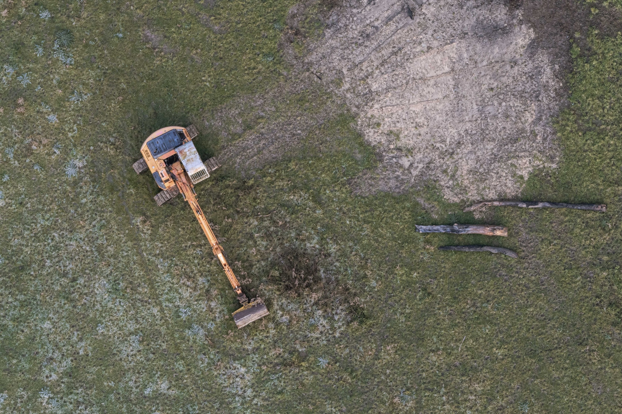 excavator construction machinery digger earth dirt grass field aerial view equipment vehicle yellow green brown landscape site work industrial outdoor digging machine