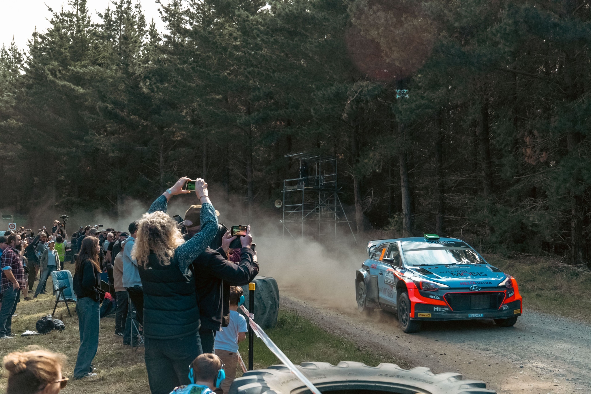 Rally Car Race Forest Spectators Dirt Road Trees Dust Blue Car Photography Event Action Motion Outdoors Daytime Racing Excitement Crowd Nature Sport Vehicle Speed Adventure Competition Landscape Pathway Greenery Enthusiasm Gathering