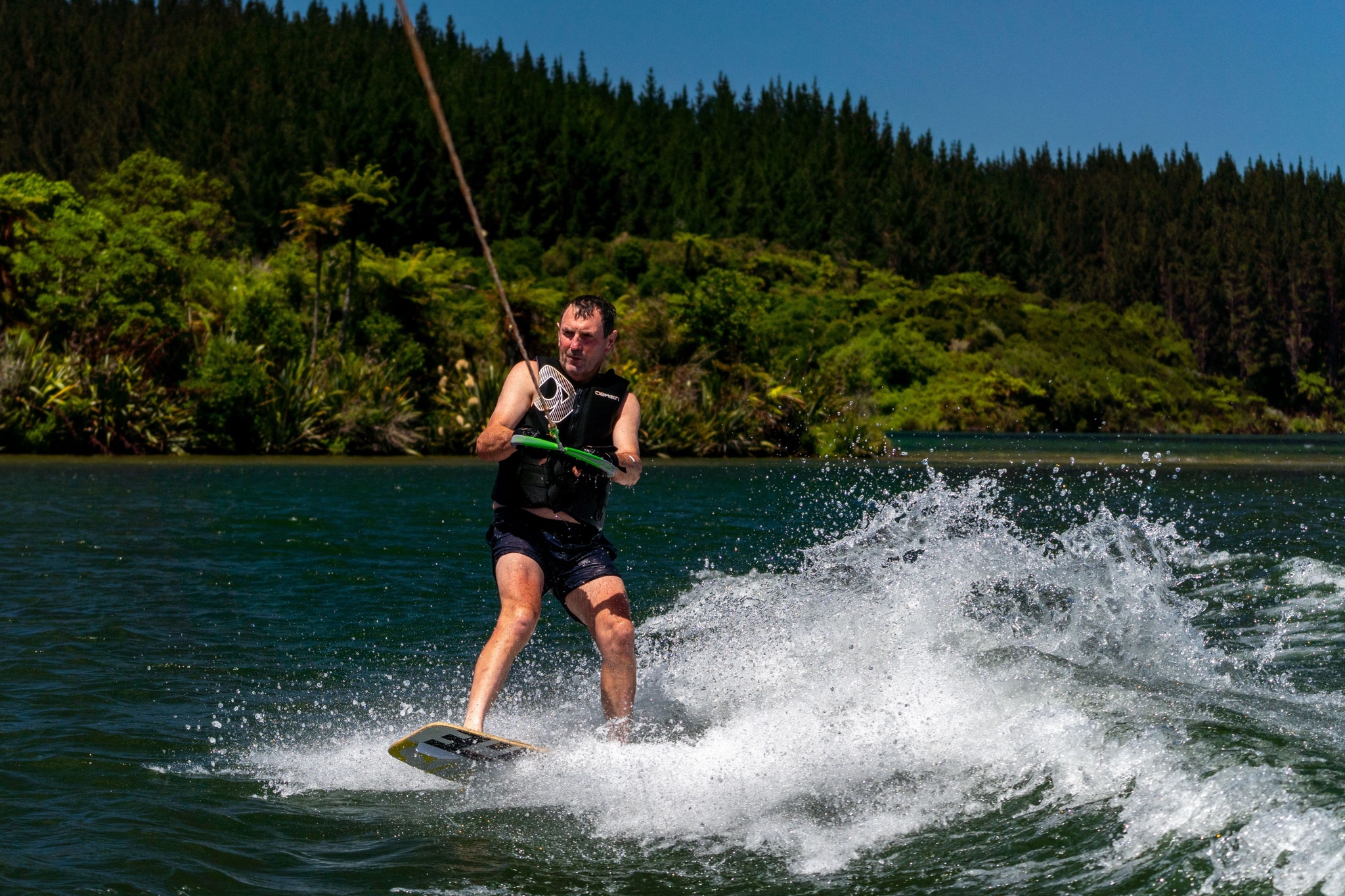 Wakeboarding Water Sports Lake Forest Trees Splash Rope Life Jacket Blue Green Sky Summer Outdoor Adventure Action Movement Waves Fun Recreation Nature Landscape Wakeboarder