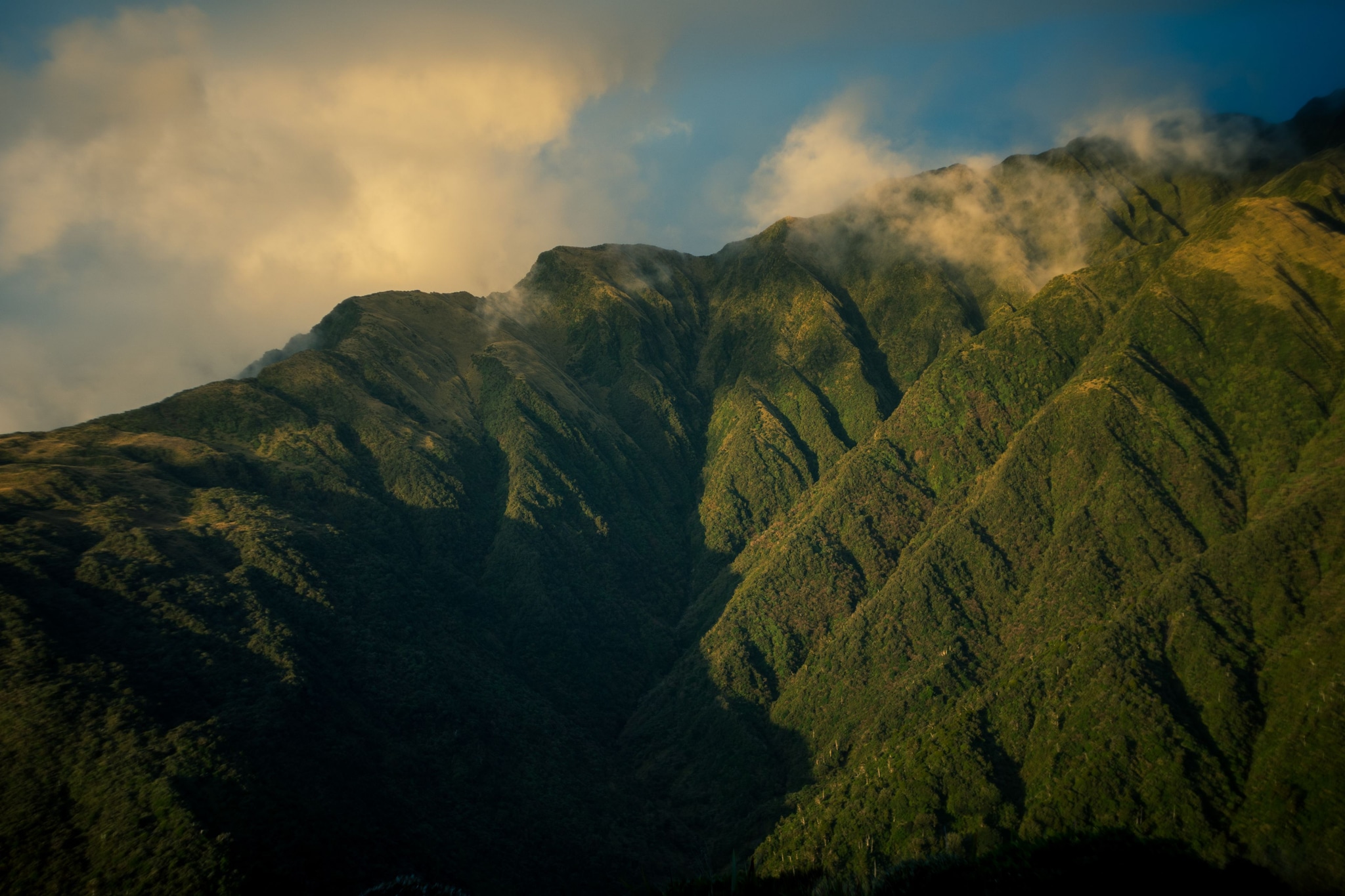mountain peak ridge slope landscape nature clouds sky sunlight shadow green blue yellow rugged terrain scenery majestic dramatic formation outdoor wilderness serene tranquil breathtaking panoramic majestic primary-color