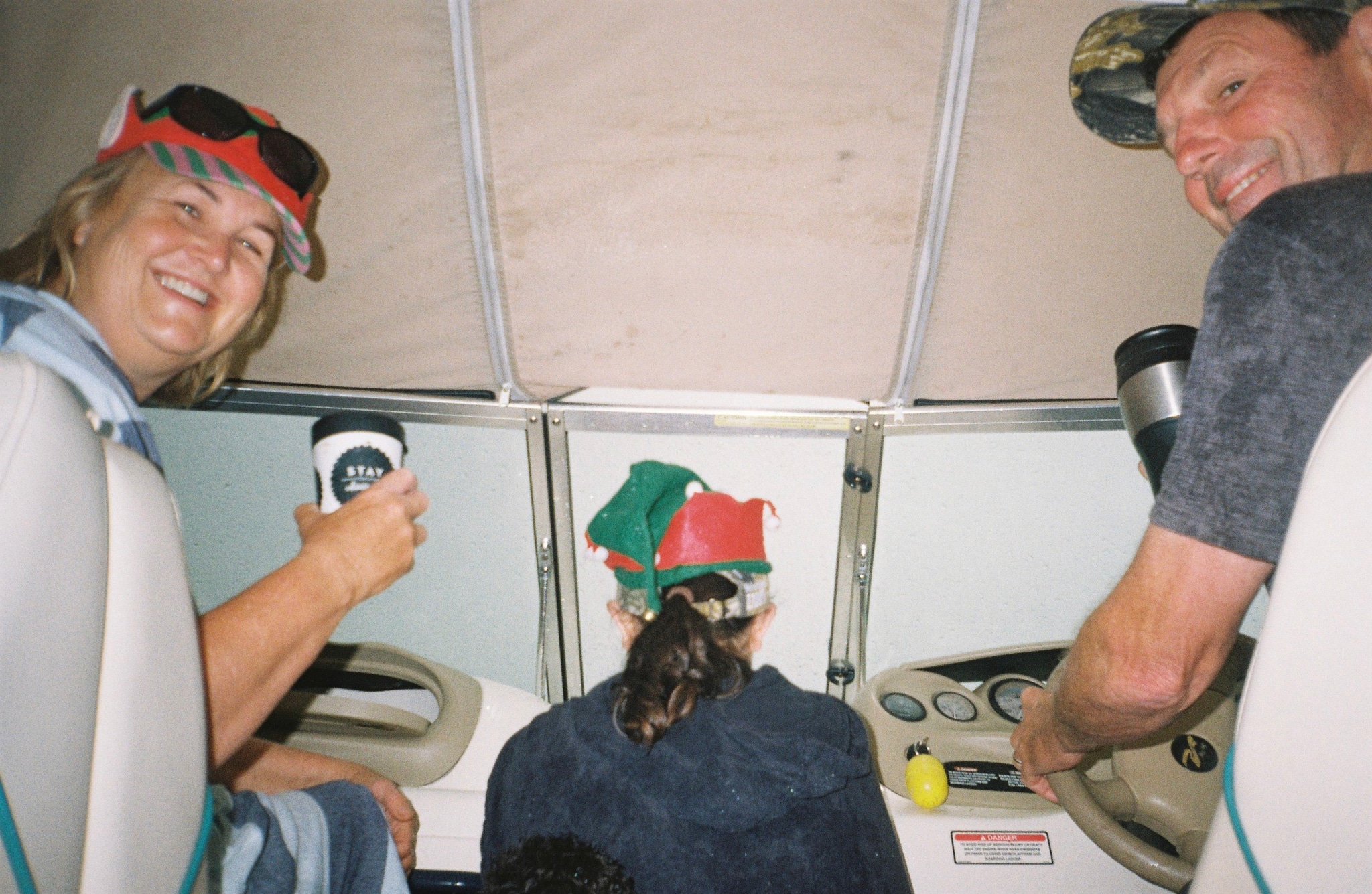 Boat Steering Wheel People Smiling Hats Sunglasses Mugs Controls Dashboard Watercraft Interior Red Green Blue White Beige Smiles Joyful Navigation Helm Boating Fun Relaxation Adventure Journey Holiday Celebration