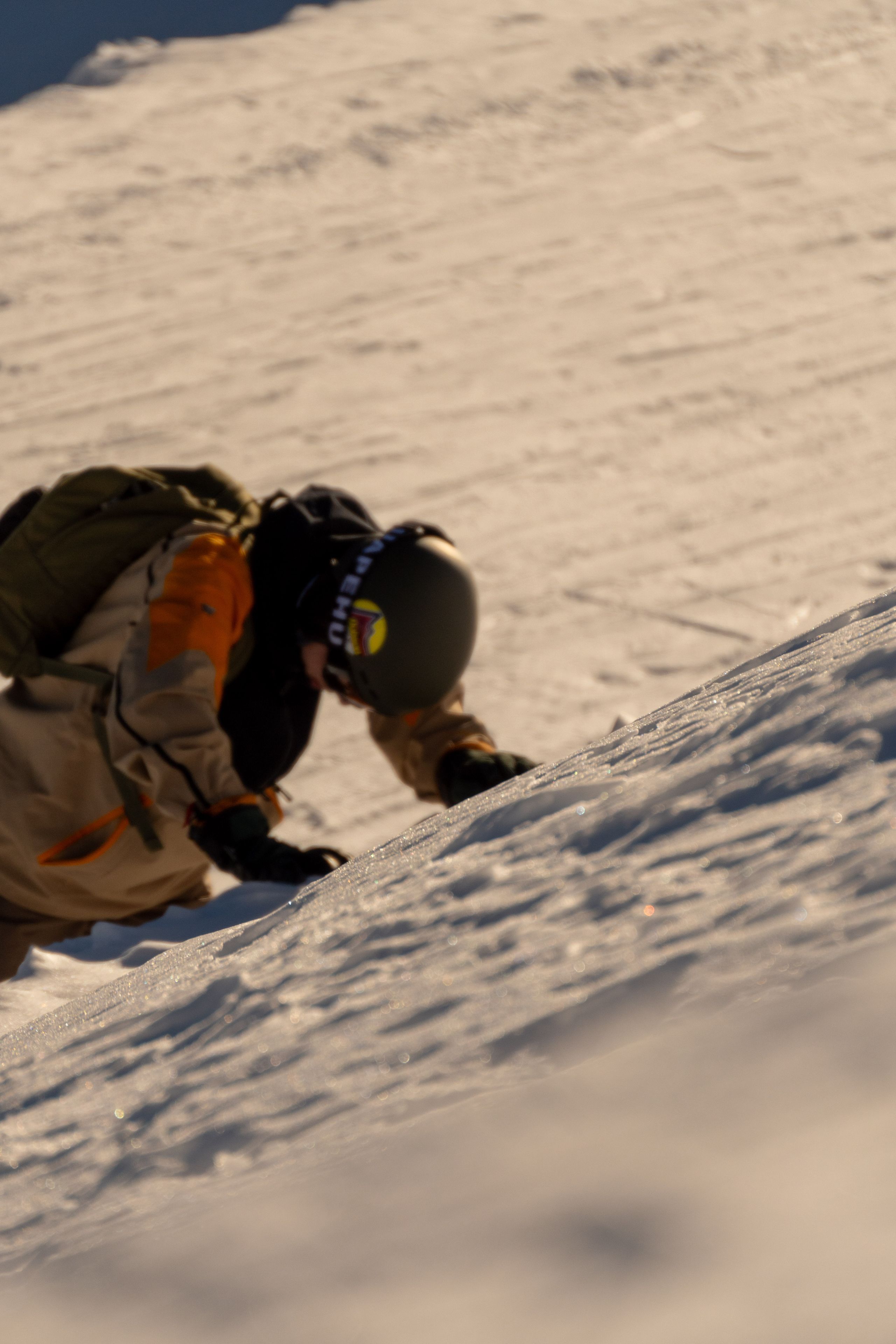 snow climbing person helmet gloves backpack slope winter outdoor gear beige